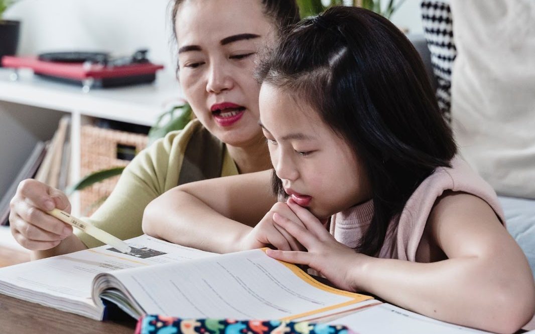 a girl studying with her mother